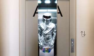 Eine Person in silbernem Anzug steht im Lift.