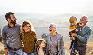 Familie lacht vor sonnigen Hügeln